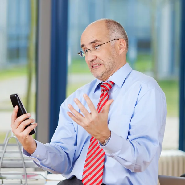 Sfrustrowany biznesmen patrząc na telefon bezprzewodowy — Zdjęcie stockowe