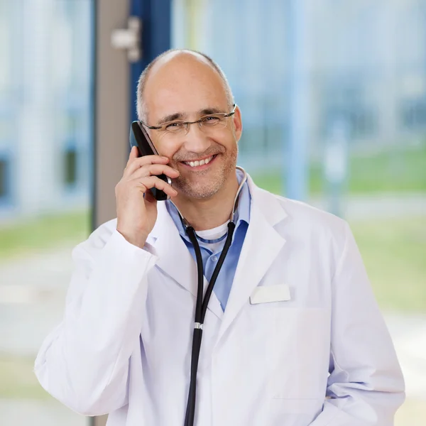 Médico sonriente usando teléfono móvil — Foto de Stock