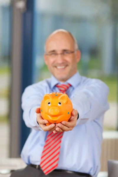 Volwassen zakenman piggy bank holding in office — Stockfoto