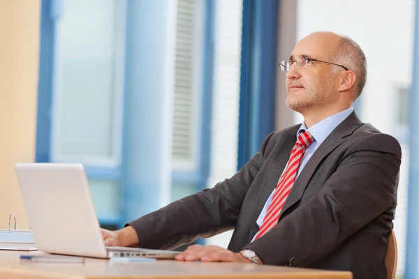 Affärsman med laptop tittar upp på skrivbord — Stockfoto