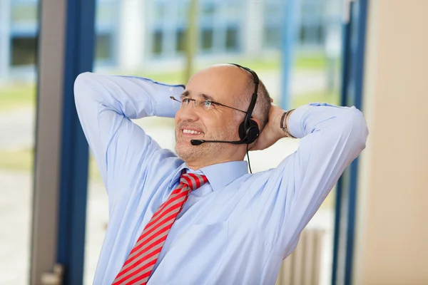 Relaxed Customer Service Executive con le mani dietro la testa — Foto Stock