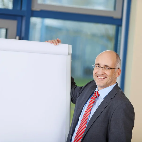 Reifer Geschäftsmann steht am Flipchart — Stockfoto