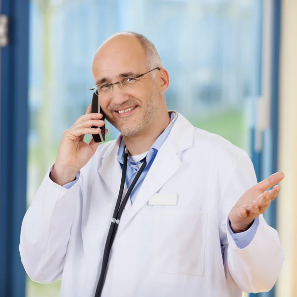 Mężczyzna lekarz gestykulacji podczas korzystania z telefonu bezprzewodowego — Zdjęcie stockowe