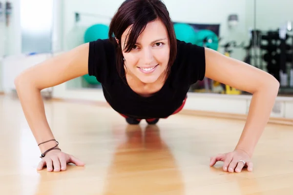 Mujer en forma haciendo flexiones en el gimnasio — Foto de Stock