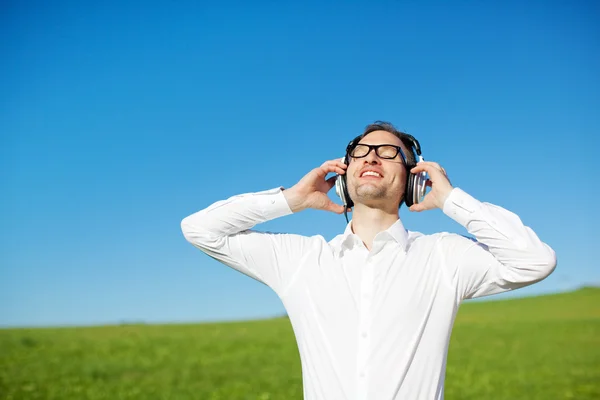 Man in a green field enjoying his music