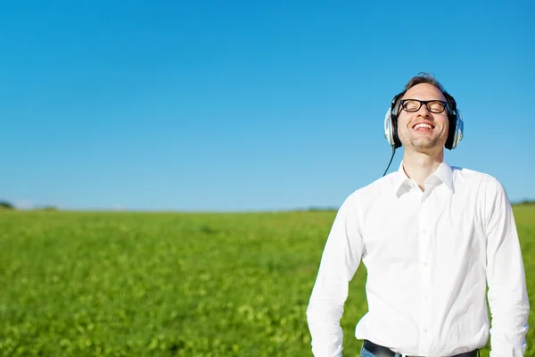 Мужчина расслабляется, слушая музыку в поле — стоковое фото