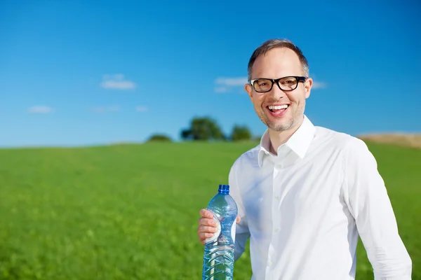 Улыбающийся человек пьет воду в бутылках — стоковое фото