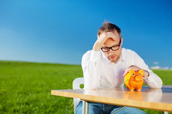 Dejected man looking at his piggy bank — Stock Photo, Image