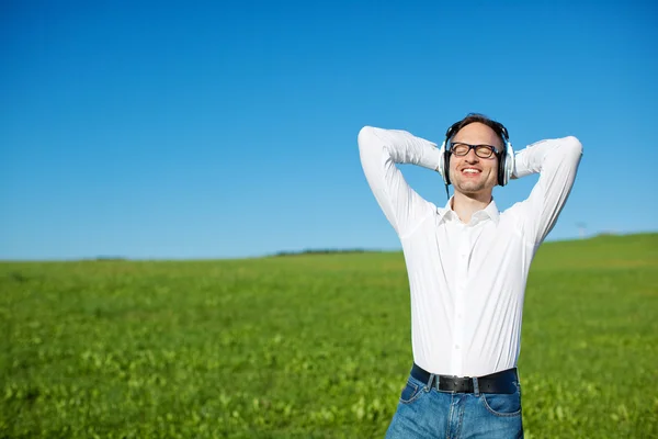 Man listening to music in a green field — Stock Photo, Image