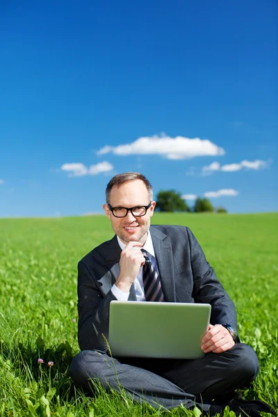 Doordachte manager zitten in een veld — Stockfoto