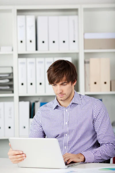 Seriöser Geschäftsmann mit Laptop im Büro — Stockfoto