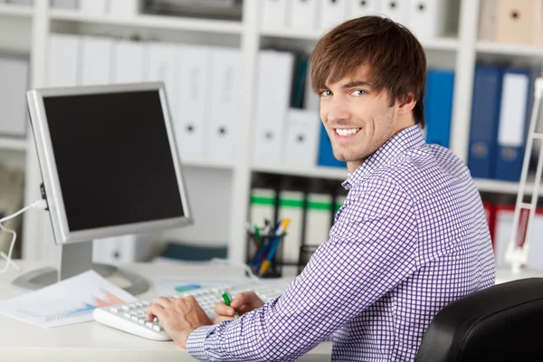Pohledný mladý podnikatel se usmívá na stůl — Stock fotografie