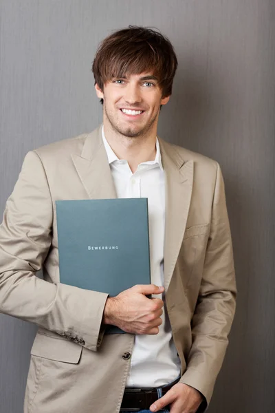 Businessman Holding Application File Against Grey Wall — Stock Photo, Image