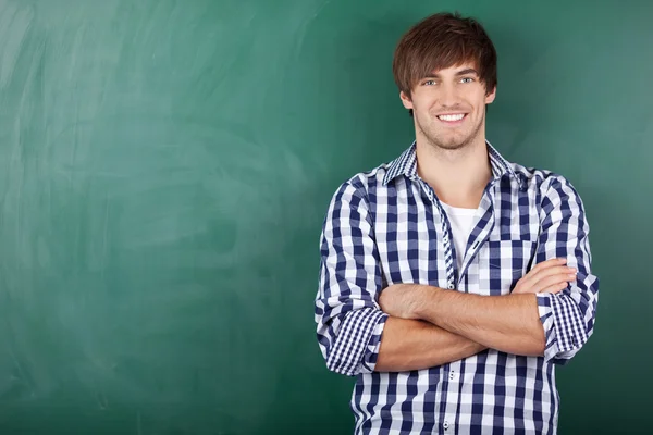 Male Student With Arms Crossed Standing Against Chalkboard — Stock Photo, Image