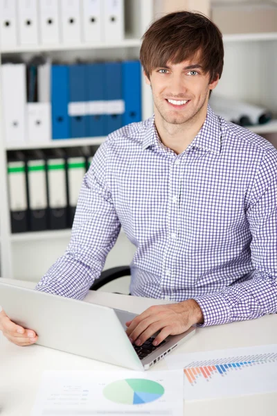 Mladý podnikatel s notebookem v kanceláři — Stock fotografie