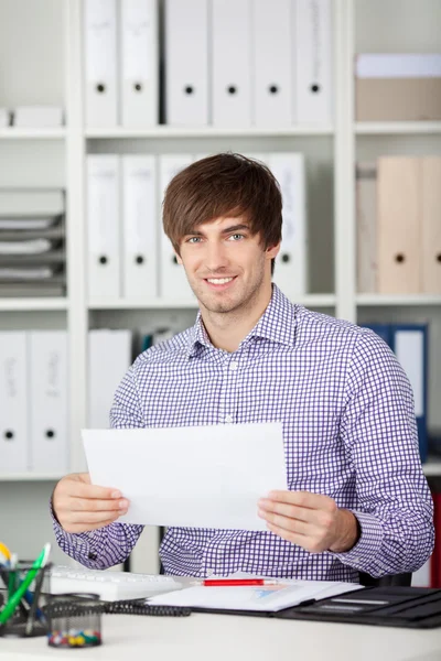 Young Businessman Holding Paper At Desk — Stock Photo, Image