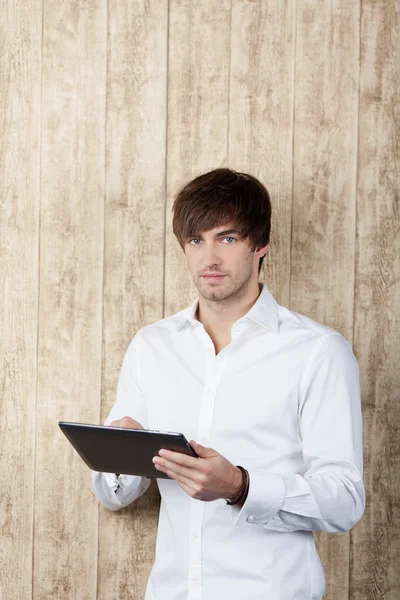 Biznesmen z cyfrowy tablicowy stojący przed drewna — Zdjęcie stockowe