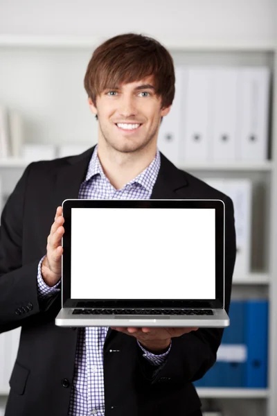 Businessman Displaying Laptop In Office — Stock Photo, Image