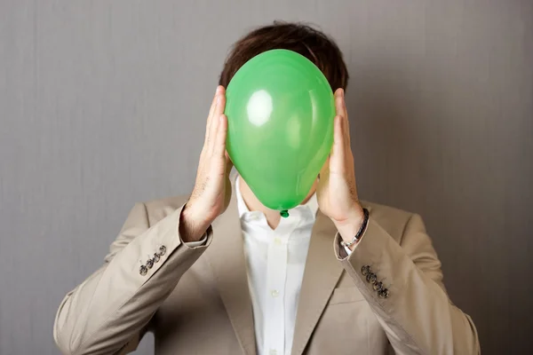 Homme d'affaires tenant ballon devant le visage — Photo