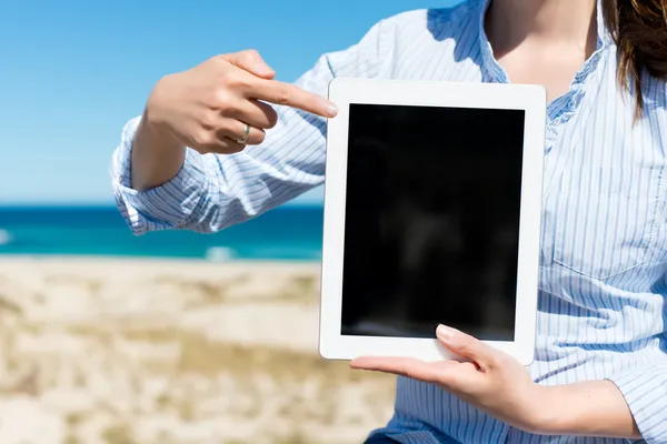 Vrouw aan het strand wijzen op tablet-pc — Stockfoto