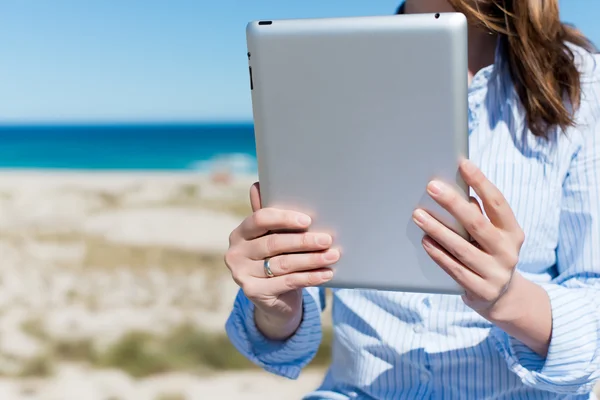 Mujer sosteniendo la tableta digital en la playa — Foto de Stock