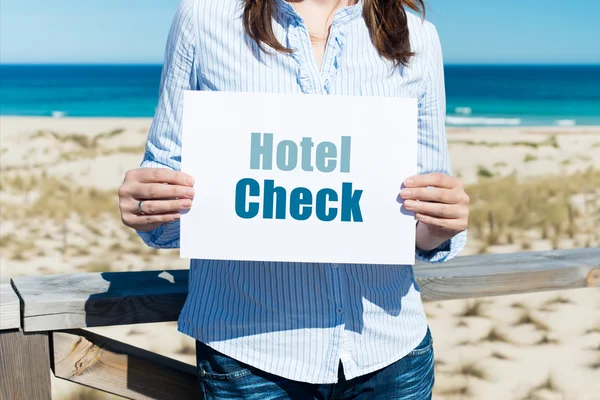 Kvinna med hotel check skylt på stranden — Stockfoto