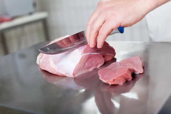 Uma faca cortando carne crua — Fotografia de Stock