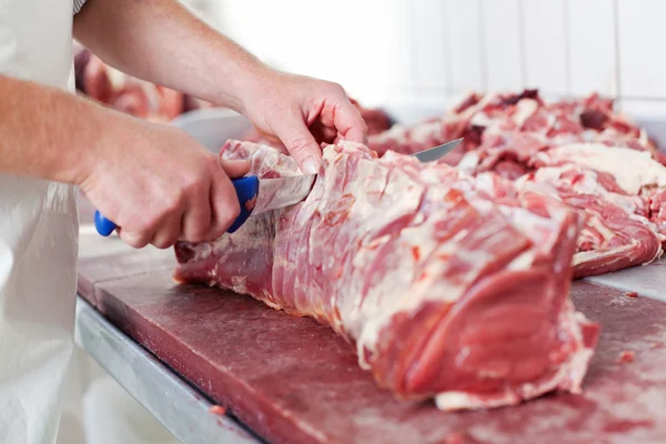 Een hand snijden rauw vlees — Stockfoto