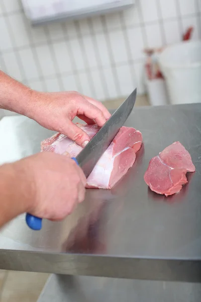 Close-up van de handen van een slager snijden steaks — Stockfoto