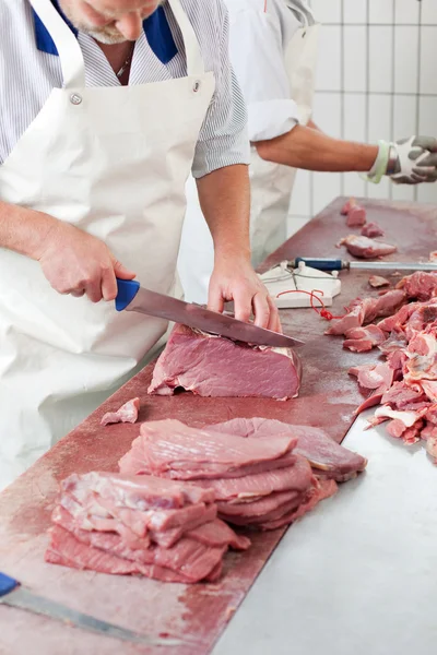 Мясник режет мясо — стоковое фото