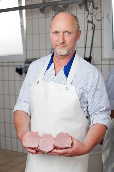 Açougueiro posando com pedaços de carne — Fotografia de Stock