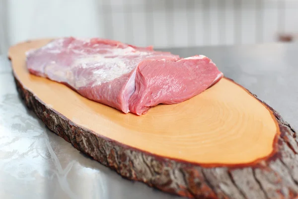 Carne fresca sobre uma tábua de carne de madeira — Fotografia de Stock