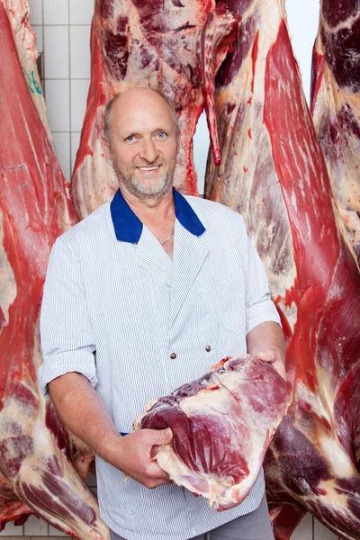 Carniceiro feliz segurando um pedaço de carne recém-cortado — Fotografia de Stock