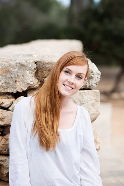 Belle femme posant contre un mur de pierre — Photo