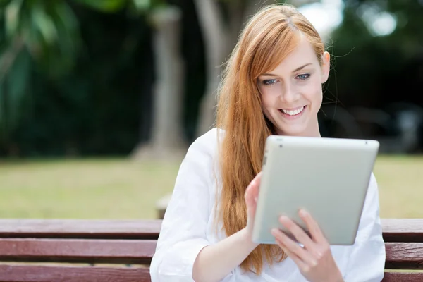 Young woman sitting in a park with her tablet-pc Stock Image