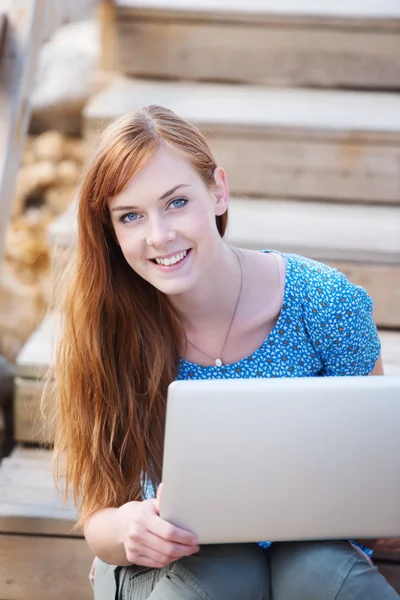 Lachende vrouw buitenshuis werken op een laptop — Stockfoto