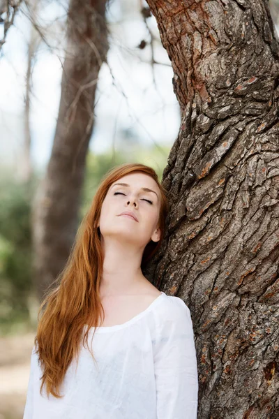 Όμορφη γυναίκα χαλαρωτικό ενάντια σε ένα δέντρο — Φωτογραφία Αρχείου