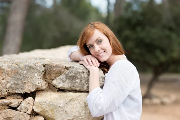 Mujer atractiva apoyada contra un muro de piedra —  Fotos de Stock