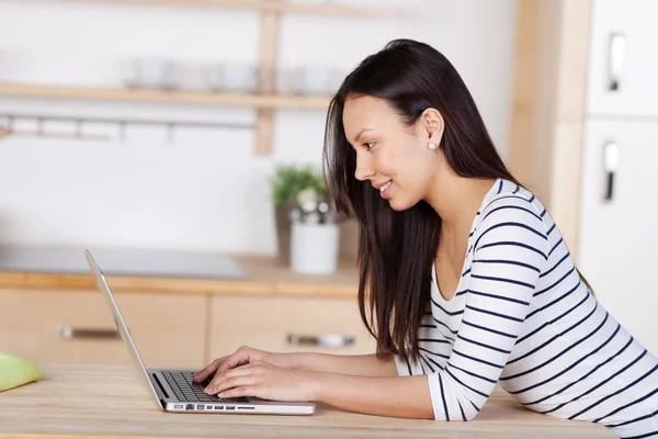 Modern woman using laptop in her kitchen — Stock Photo, Image