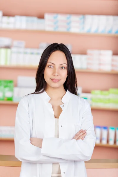 Young saleswoman with folded arms in a drug store — Stock Photo, Image