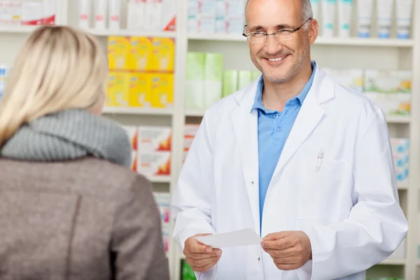 Farmacista Holding prescrizione carta mentre guardando il cliente — Foto Stock