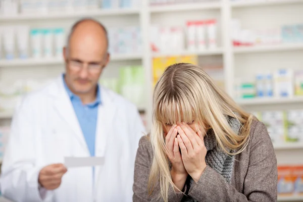 Estornudo del cliente con el papel de la prescripción de la lectura del farmacéutico —  Fotos de Stock