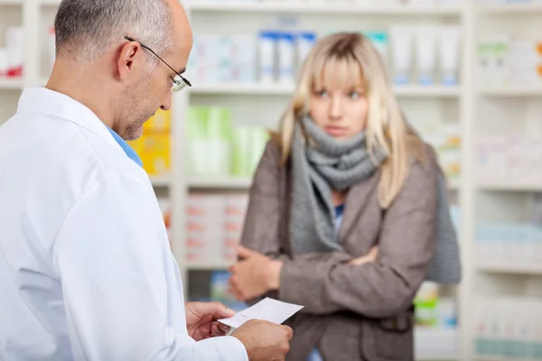 Farmacêutico leitura prescrição enquanto cliente feminino tremores — Fotografia de Stock