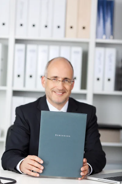 Empresario sosteniendo libro de solicitud en la mesa — Foto de Stock