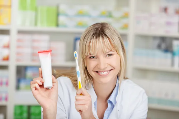 Apotheker tandpasta en een tandenborstel in apotheek bedrijf — Stockfoto