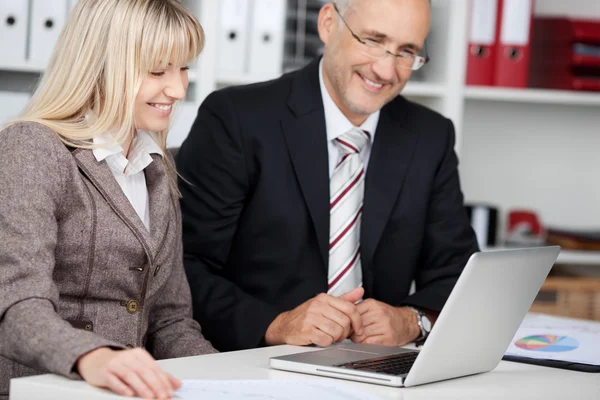 Two colleagues looking smiling at laptop — Stock Photo, Image