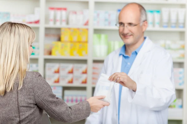 Farmacéutico que da la bolsa de la medicina al cliente — Foto de Stock