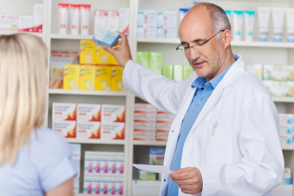 Farmacêutico tirando medicamentos prescritos para o cliente — Fotografia de Stock