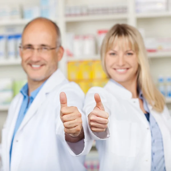 Фармацевты показывают большие пальцы в аптеке — стоковое фото