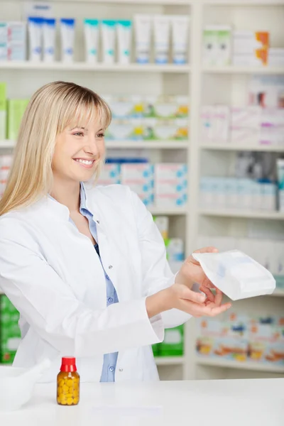 Farmacéutica femenina dando bolsa de papel de la medicina en el mostrador — Foto de Stock